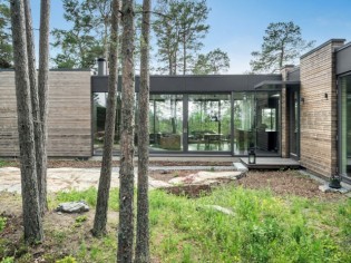 En Suède, une maison en bois se fond dans une forêt de pins