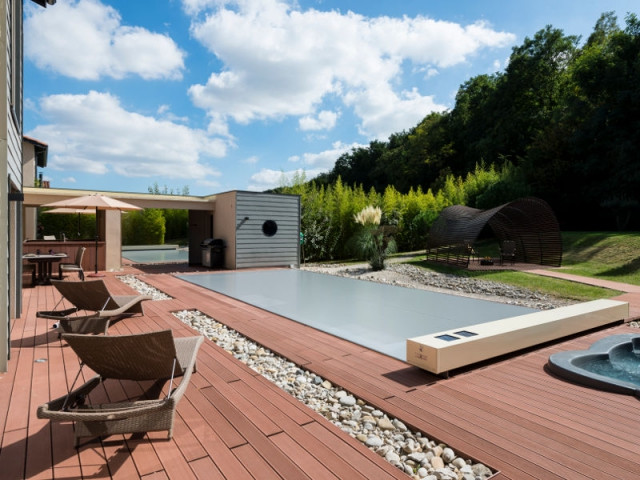 Une couverture de piscine dissimulée dans une terrasse paysagère