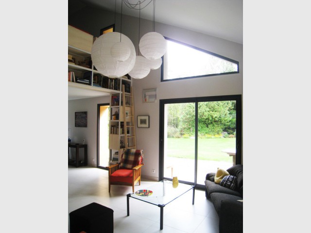 Un salon bibliothèque lumineux grâce à une fenêtre triangulaire - Restructuration d'une maison en Haute-Savoie