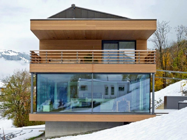 Une maison de bois posée sur un socle de béton - Un chalet ouvert sur la montagne