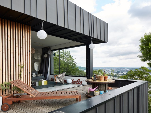 Une terrasse panoramique - Une maison en zinc noir posée sur un mur en brique