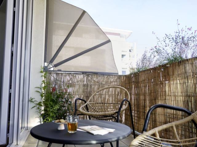 Un éventail pour se cacher du soleil sur un balcon