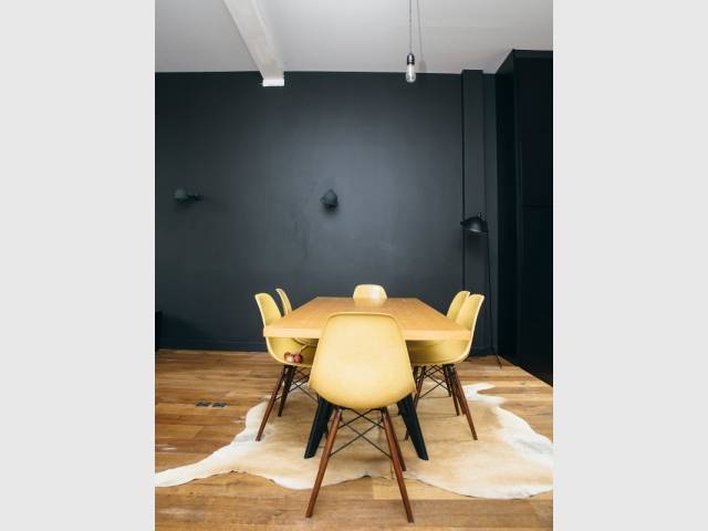 Une salle à manger aux murs noir mat