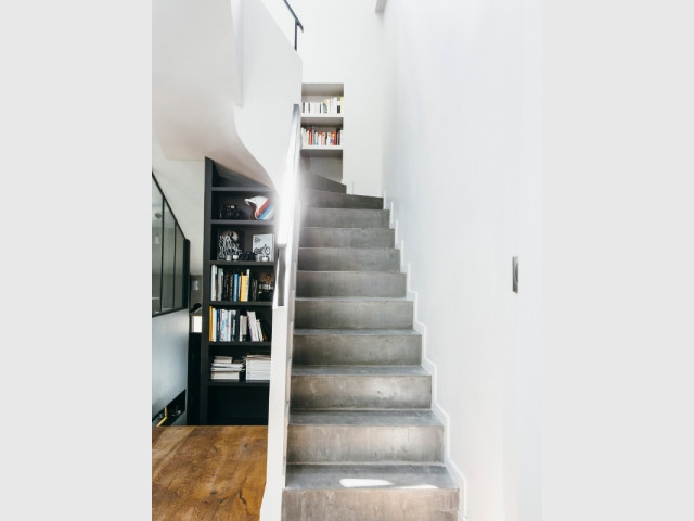 Un escalier baigné de lumière, caché derrière une bibliothèque