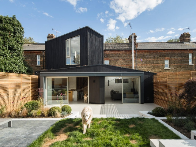 Une extension bois noir sur une maison en brique