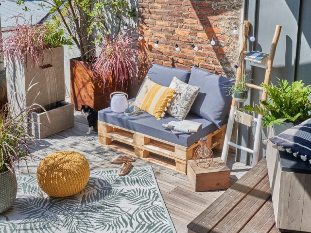 Un canapé en palettes et ses coussins gris sur un balcon