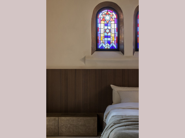 Dans la chambre, les vitraux de l'ancienne chapelle apportent une touche de couleur