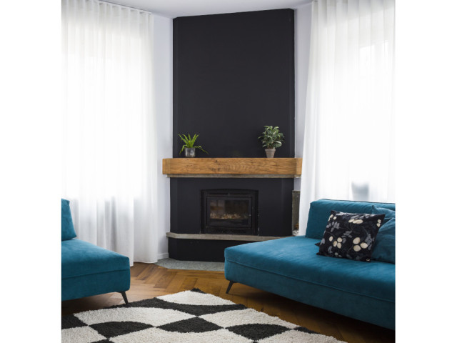 Dans le salon, la cheminée peinte en noir est encadrée de deux canapés en velours bleu roi