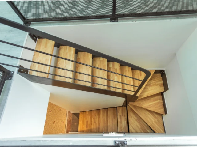 Un escalier en métal et bois qui laisse passer la lumière