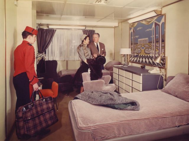 Photographie montrant un mousse de sonnerie apportant les bagages des passagers dans leur cabine de la première classe à bord du paquebot France (CGT 1962-1977).