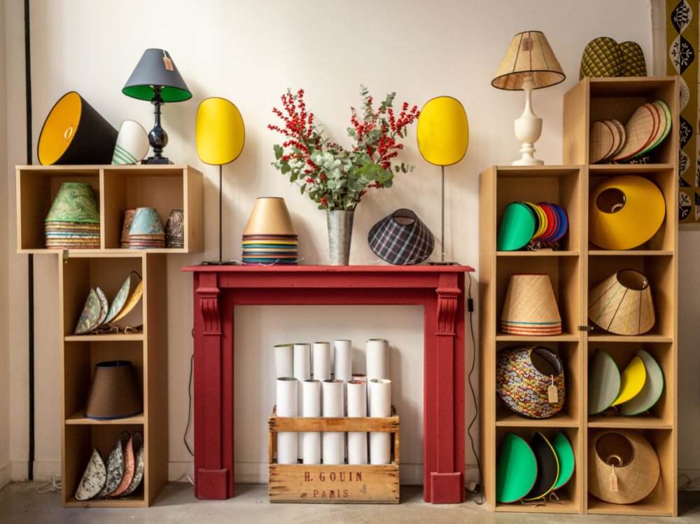 L'atelier-boutique avec la fausse chemin&eacute;e et ses &eacute;tag&egrave;res charg&eacute;es d'abat-jour