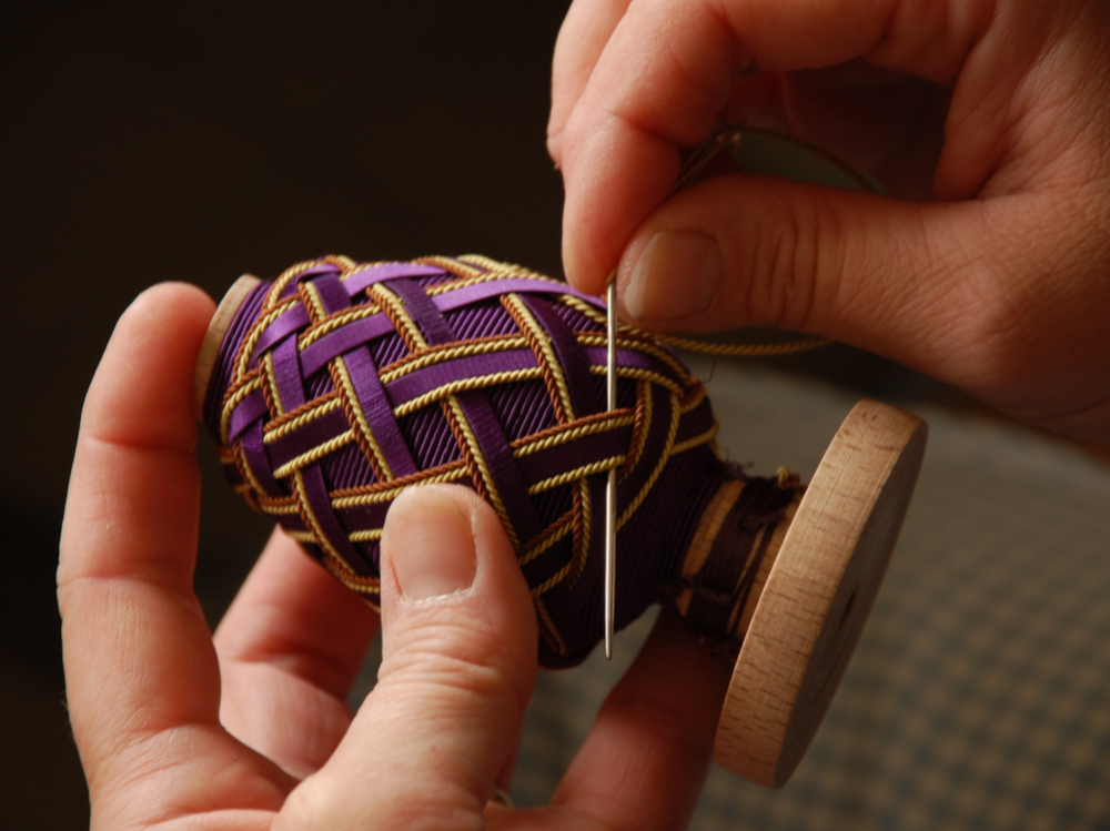 Un gland en cours de fabrication dans l'atelier Declercq Passementiers : la t&ecirc;te, mont&eacute;e sur un moule en bois, est habill&eacute;e &agrave; l'aiguille.