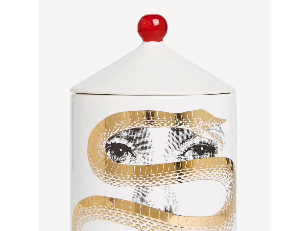 Chez Fornasetti, la bougie se pr&eacute;sente dans un pot en c&eacute;ramique d&eacute;cor&eacute; des motifs de la maison milanaise.